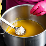 **Image Prompt:** "A person wearing gloves and safety glasses carefully stirring a mixture of lye solution (in a stainless steel pot) and oils (coconut, olive, palm) together. The mixture should look like it's starting to thicken, resembling honey, with hints of natural colors (yellow from turmeric, pink from beetroot, green from spirulina). Safety first!"